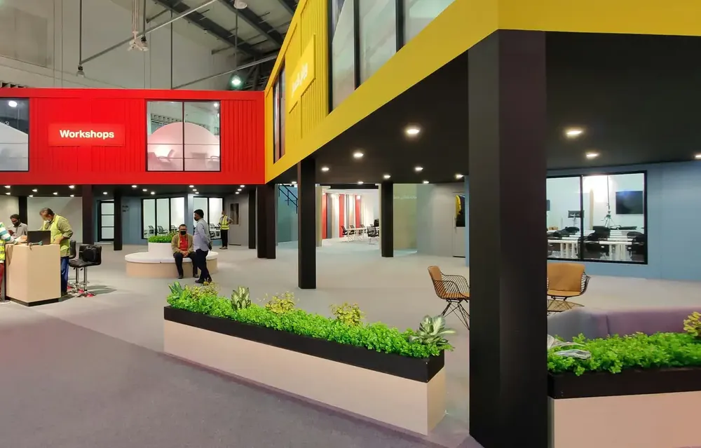 A custom two-storey exhibition stand being built in a trade fair hall, with crew in safety vests